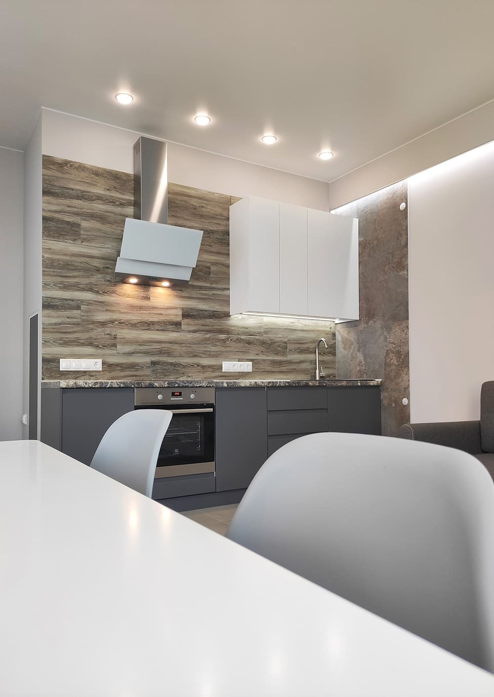 Кухонный гарнитур с подсветкой, белыми шкафами и древесной отделкой фартука