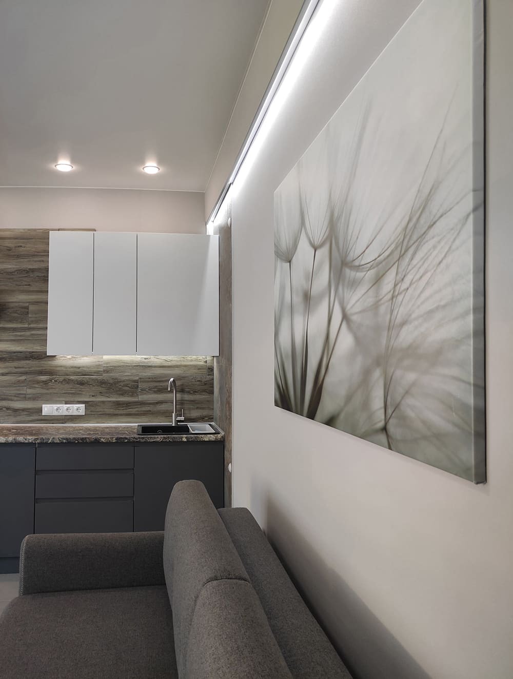 Совмещённая кухня-гостиная с белыми шкафами, серыми фасадами и картиной на стене