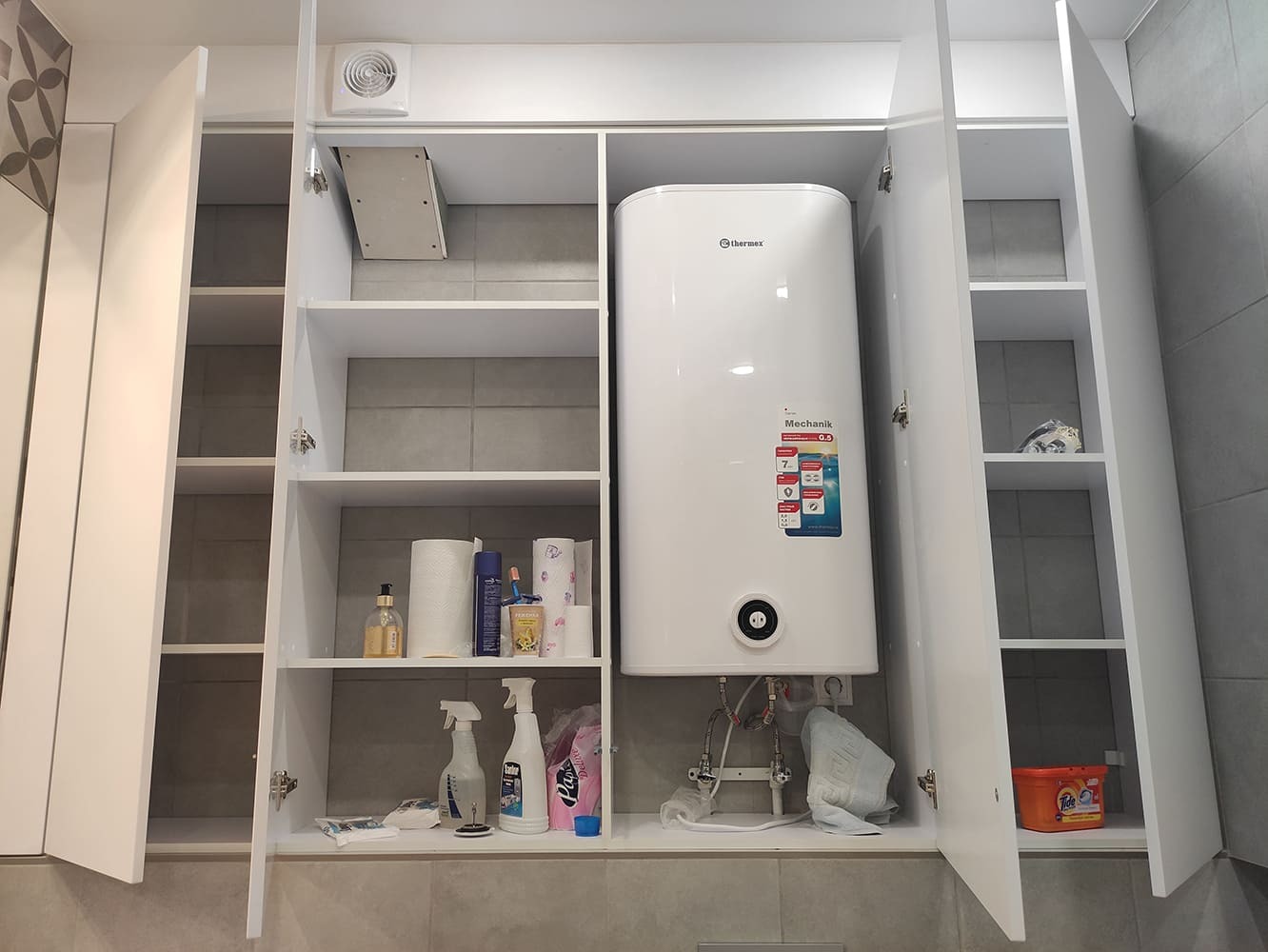 Санузел с открытыми шкафами, полками и установленным водонагревателем