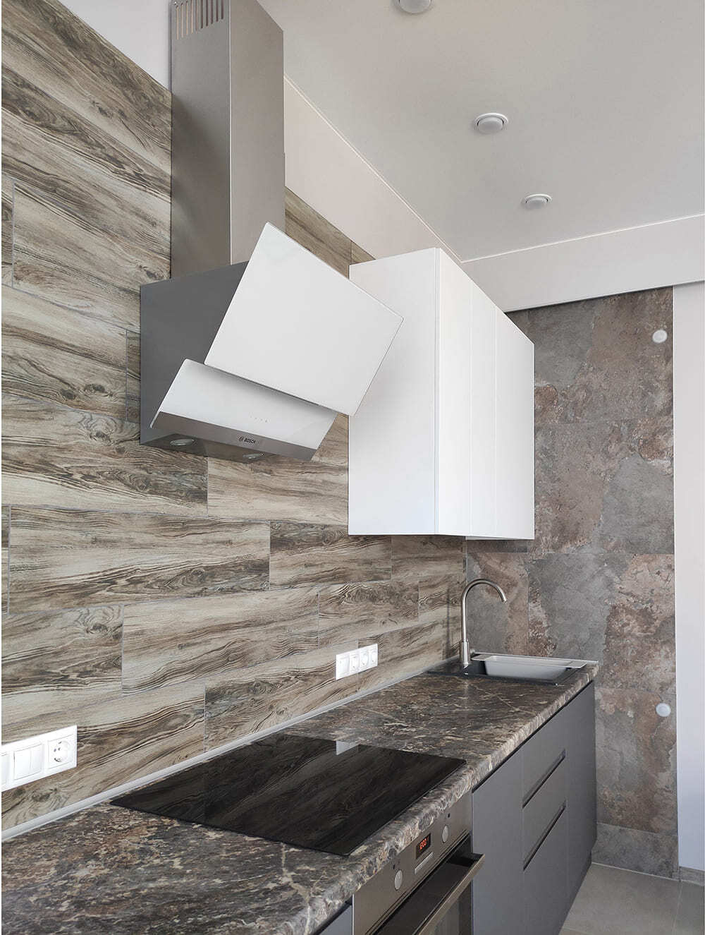 Кухонная рабочая зона с варочной поверхностью, вытяжкой и каменной столешницей