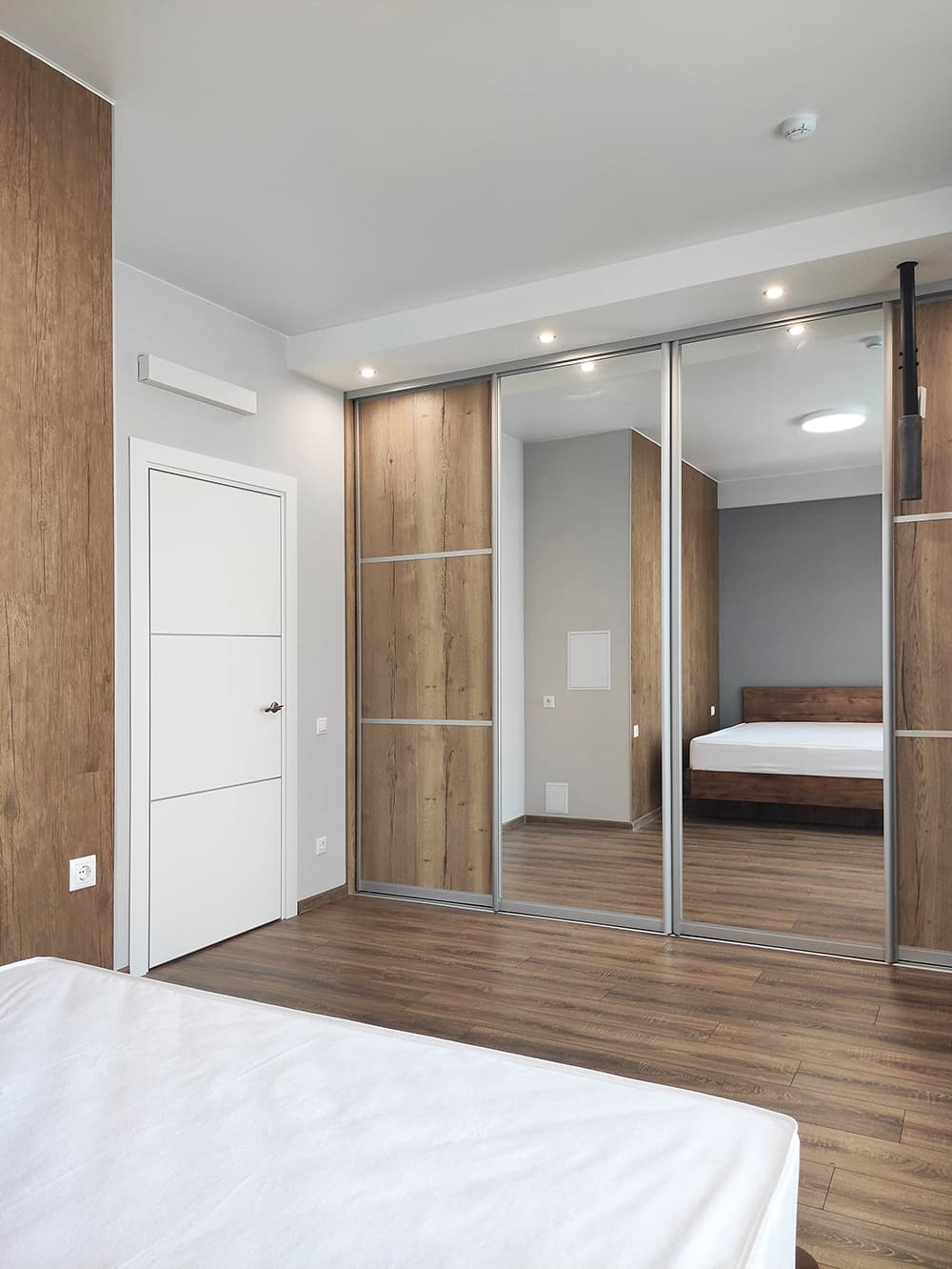 Встроенный шкаф-купе с зеркальными дверями в современном дизайне спальни