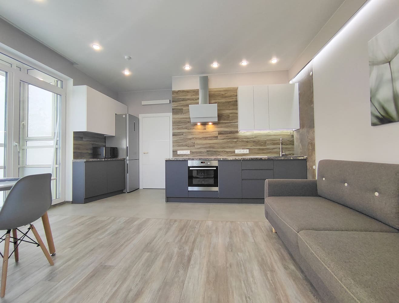 Объединённая кухня-гостиная с зонированием и современным освещением