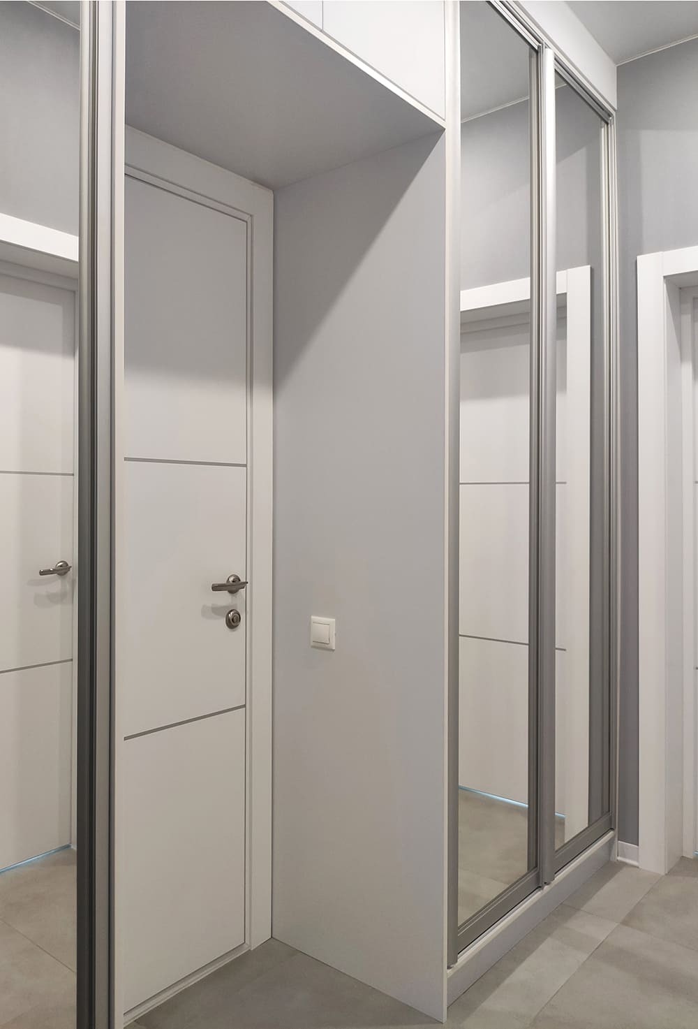 Светлая современная прихожая с большим зеркальным шкафом-купе и минималистичной отделкой