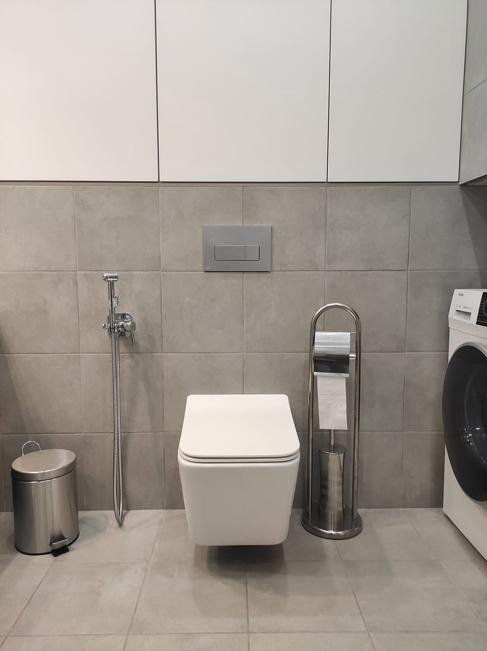 Интерьер санузла с подвесным унитазом, серыми плитами и верхними встроенными шкафами  2