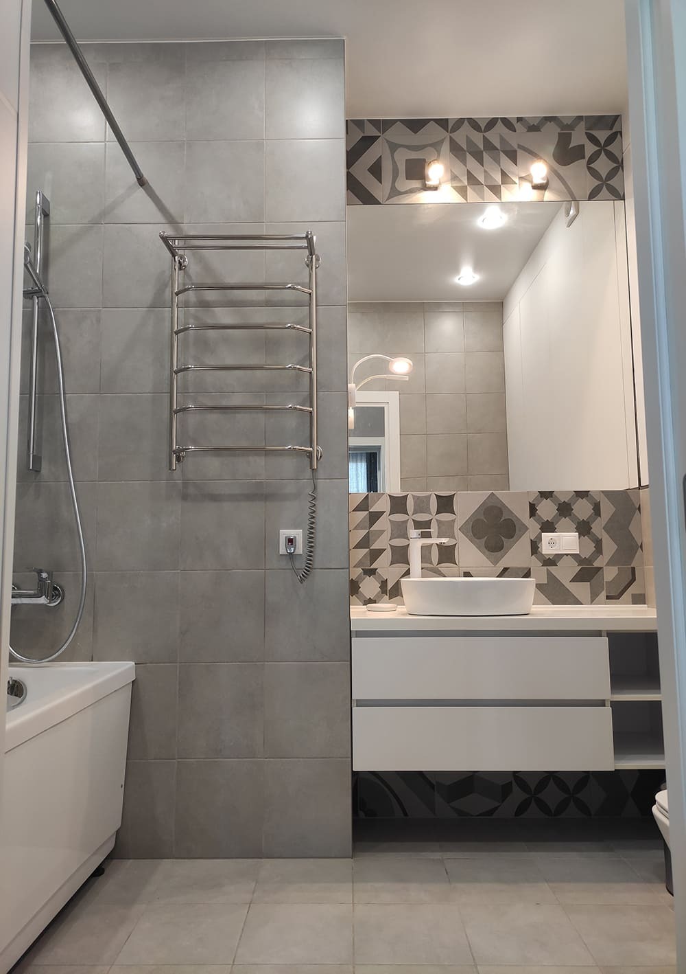 Современная ванная с полотенцесушителем, плиткой и зеркалом над раковиной