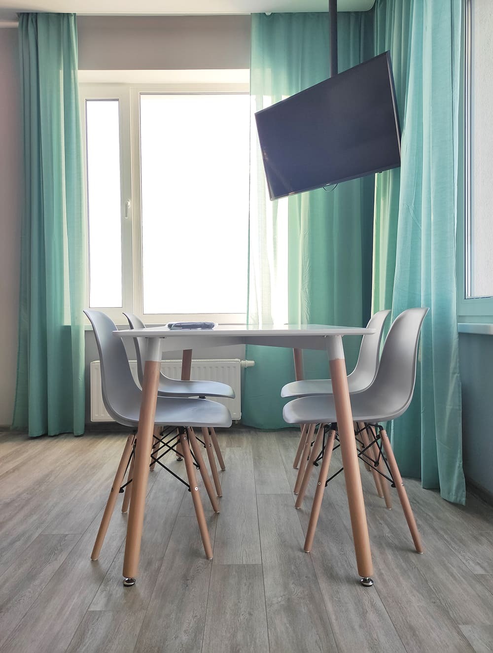 Дизайн-проект обеденной зоны с круглым столом, бирюзовыми шторами и настенным телевизором