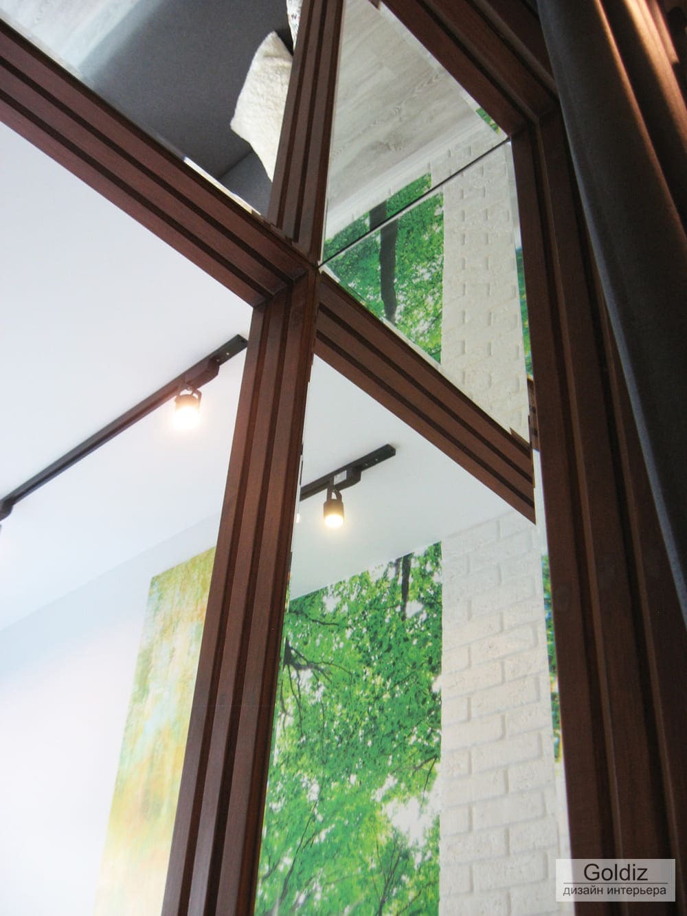 Декоративная деревянная перегородка и трековое освещение в интерьере лоджии с акцентной зелёной фотопанелью на стене