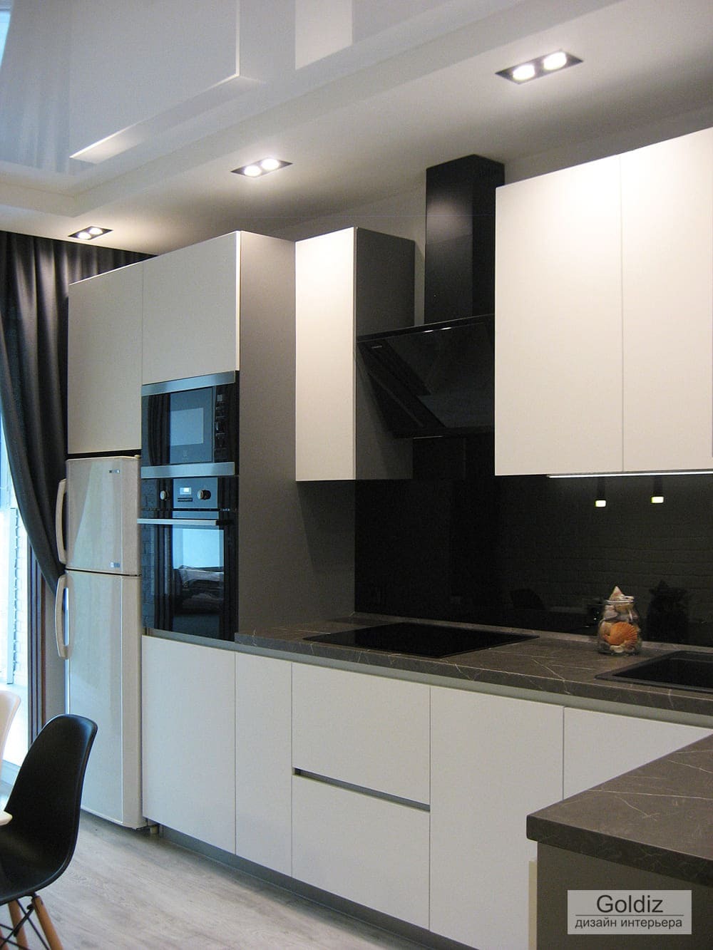 Блок кухни с белыми фасадами, чёрной вытяжкой, встроенной техникой и функциональной угловой рабочей зоной в современном стиле