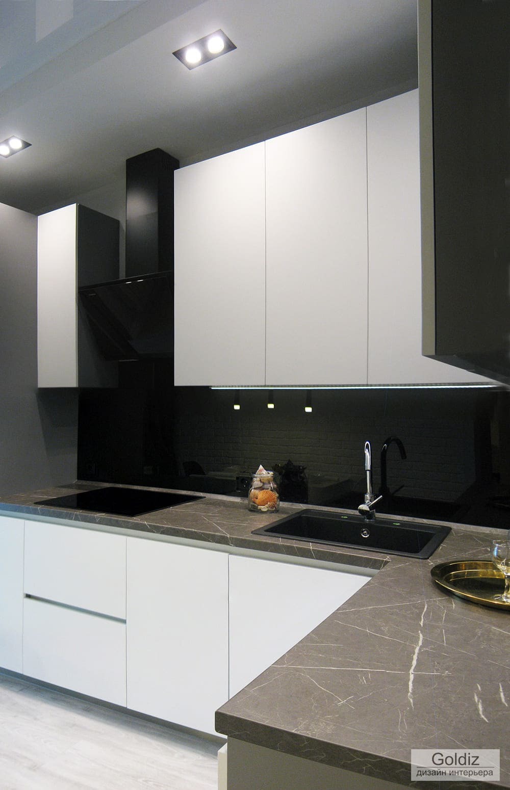 Рабочая зона кухни с чёрной вытяжкой, стеклянным фартуком и плавными линиями модулей — современная интерпретация минимализма