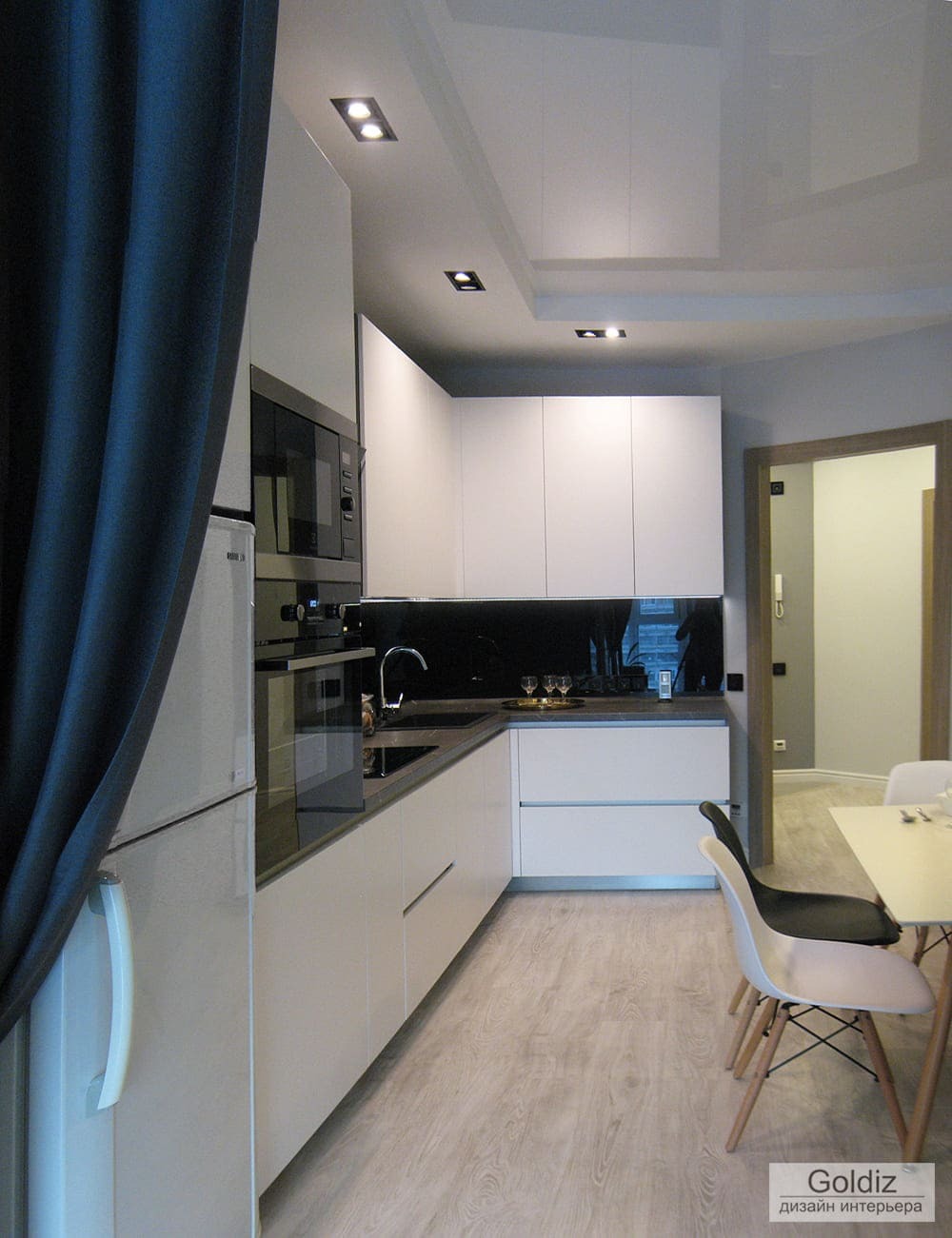 Современная кухня с белыми фасадами, чёрным стеклянным фартуком и встройкой техники — функциональное решение в минималистичном стиле