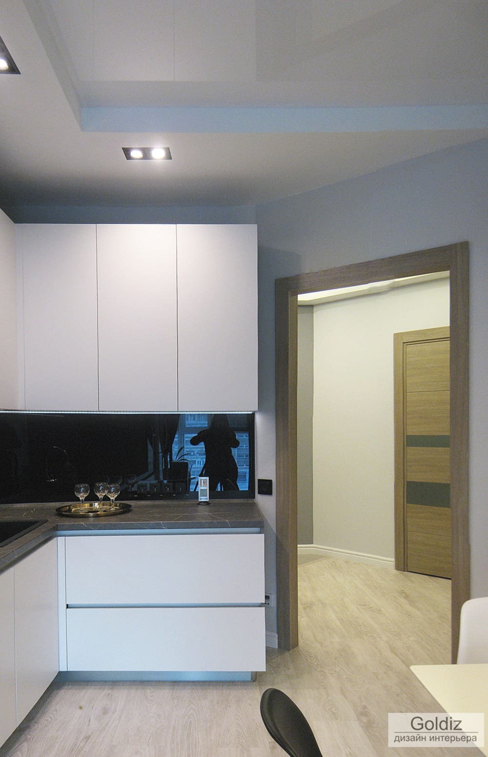 Угловая планировка кухни с белыми и серыми фасадами, встроенным холодильником и компактной рабочей зоной