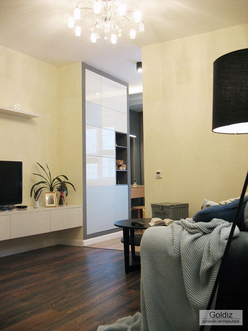 Современная гостиная со светлыми стенами, темным деревянным полом и встроенными системами хранения