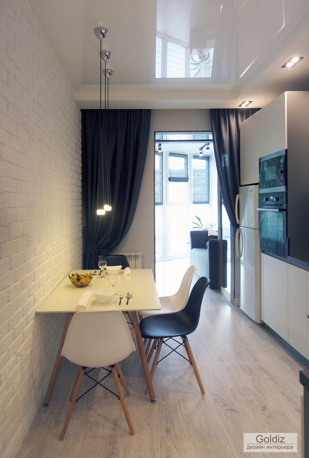 Столовая зона с белым столом, контрастными тёмными шторами, подвесным освещением и фактурной кирпичной стеной — современный минимализм