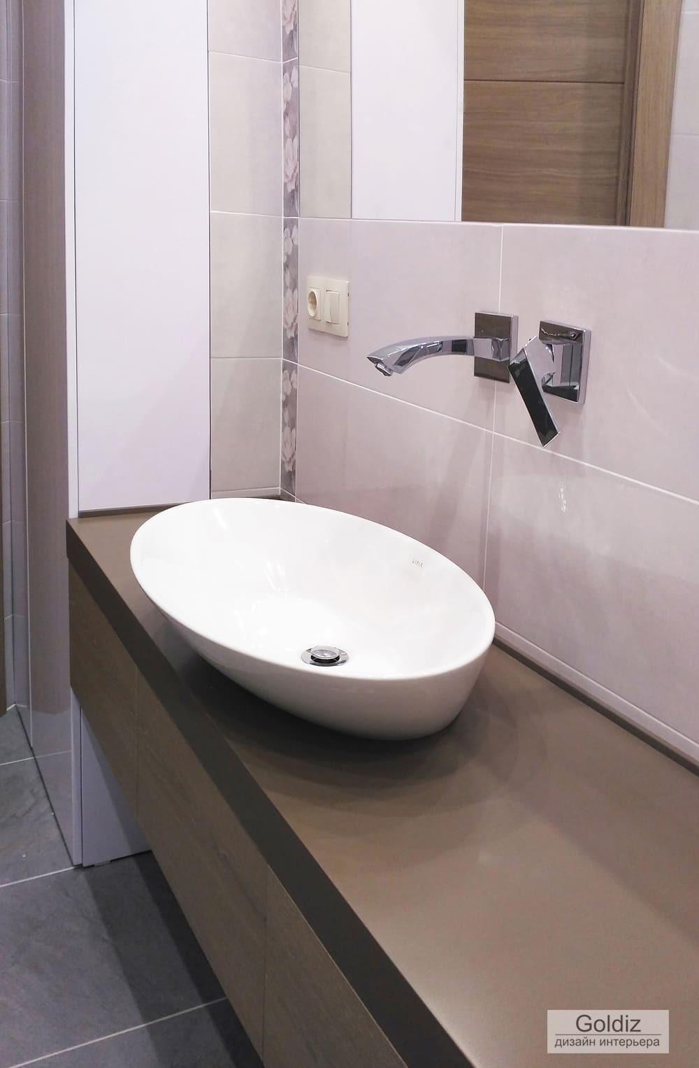 Белая овальная раковина на функциональной тумбе и настенный смеситель в светлой ванной комнате &mdash; современный минималистичный интерьер