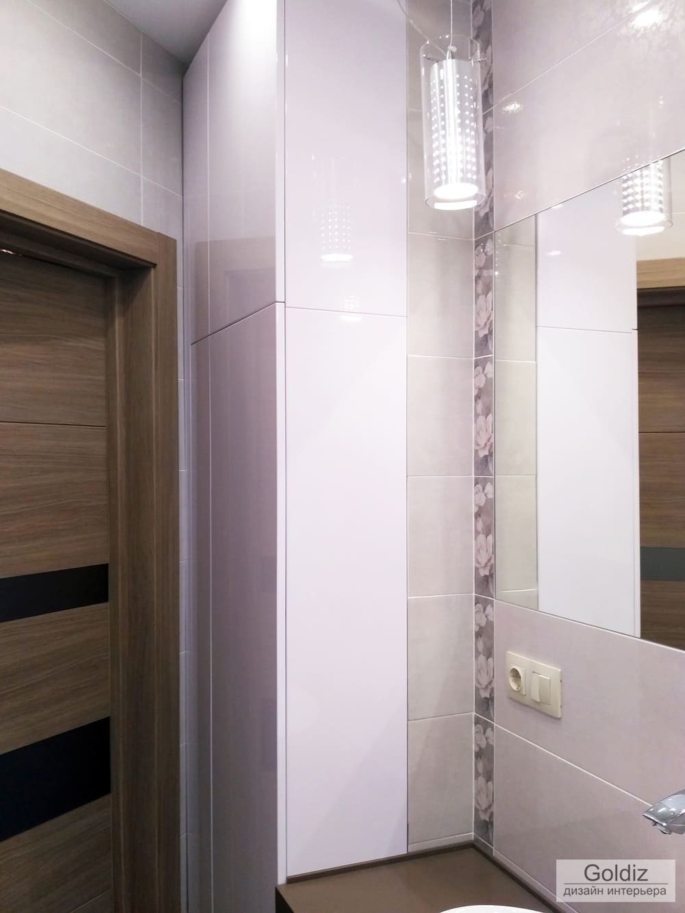 Зеркало с подвесной подсветкой, белый глянцевый шкаф и тумба под раковину в оформлении современной ванной комнаты