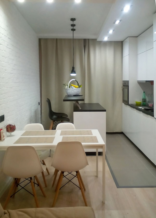 Яркая кухня с островом и современным освещением, что делает пространство удобным и функциональным для готовки и общения.