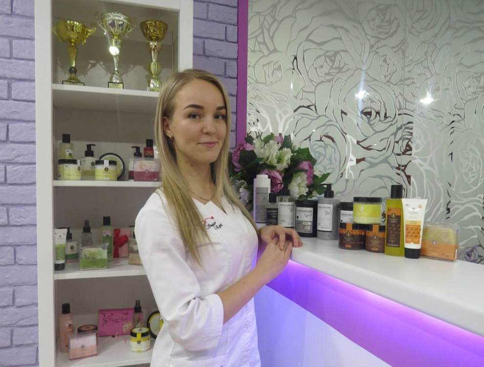 Работники салона красоты, стоящие у стильного ресепшн, на фоне сертификатов и наград, что подчеркивает профессионализм и высокое качество услуг.